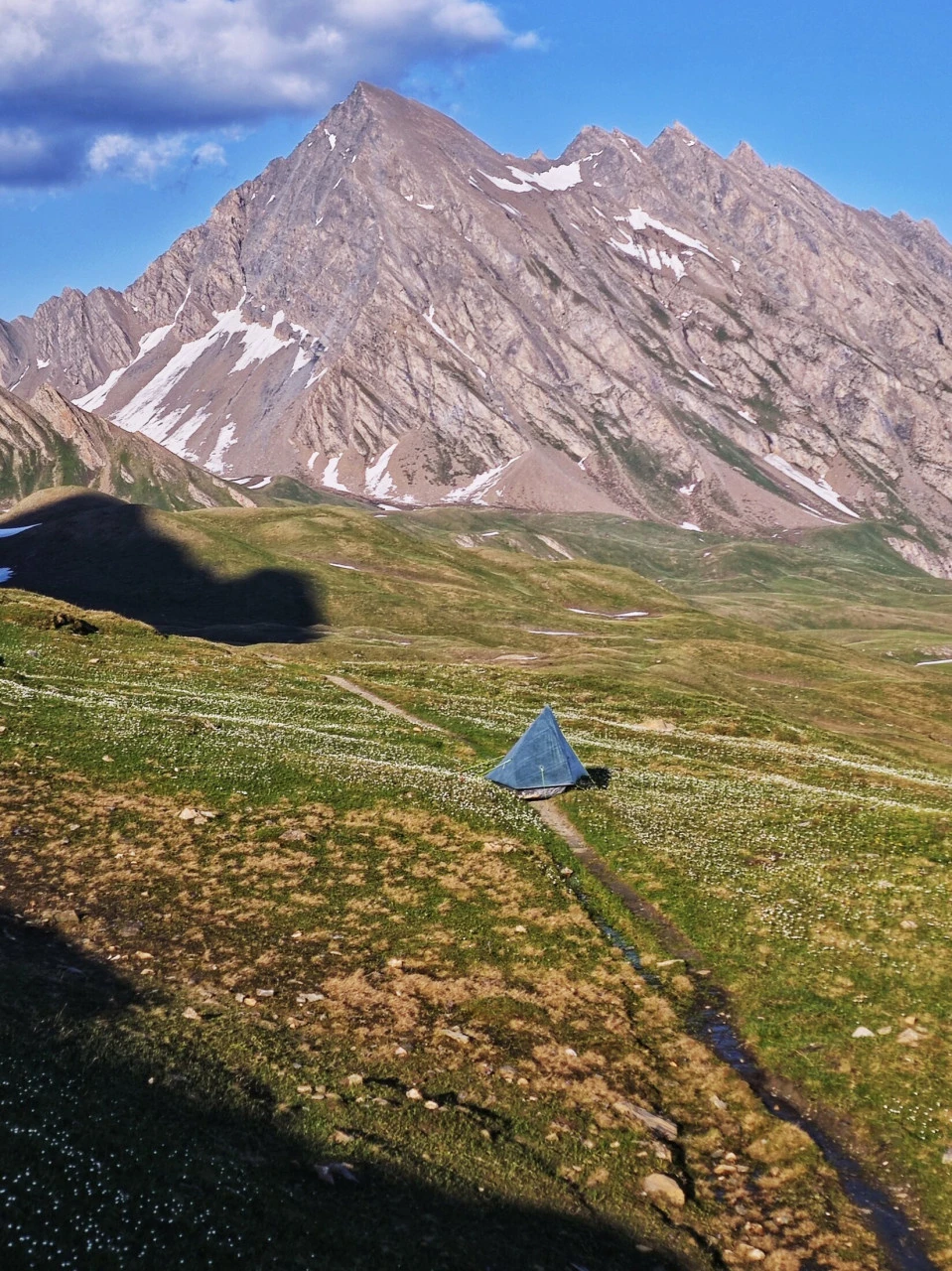 Telt rejst på en fjeldeng på TMB i begyndelsen af juni, lillebitte under toppen med sneen stadig til stede: en stemning, der ikke længere findes, når højsæsonen er i gang